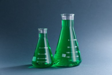Photo of Laboratory glassware with green liquid on grey background