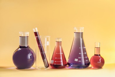 Photo of Laboratory glassware with colorful liquids on beige background