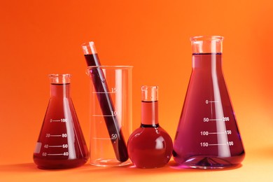 Photo of Laboratory glassware with red liquid on orange background
