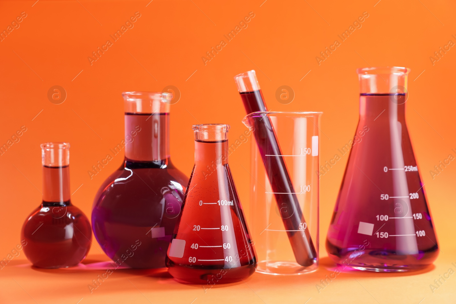 Photo of Laboratory glassware with red liquid on orange background