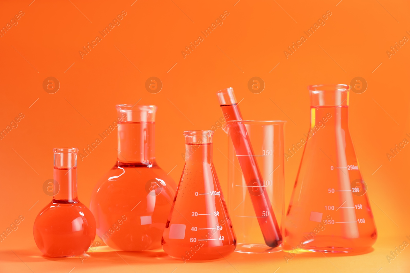 Photo of Laboratory glassware with color liquid on orange background