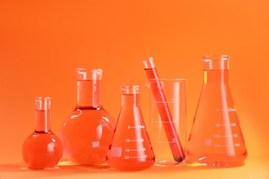 Photo of Laboratory glassware with color liquid on orange background