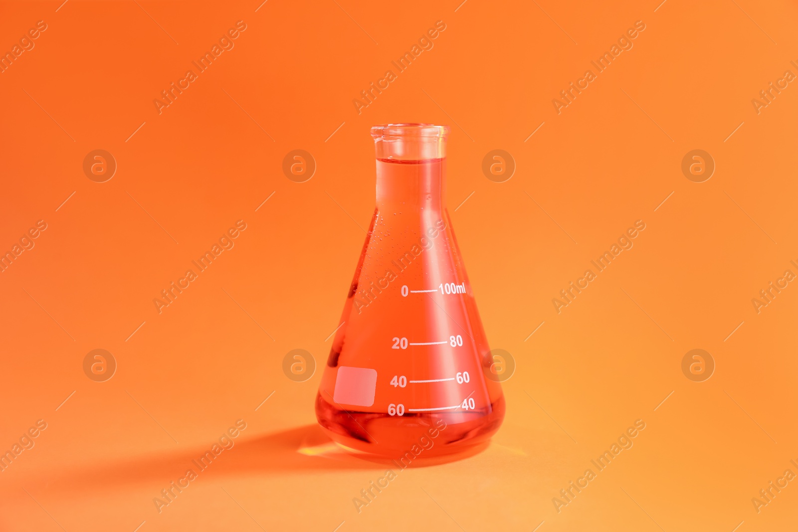 Conical flask with color liquid on orange background Photo of Conical flask with color liquid on orange background