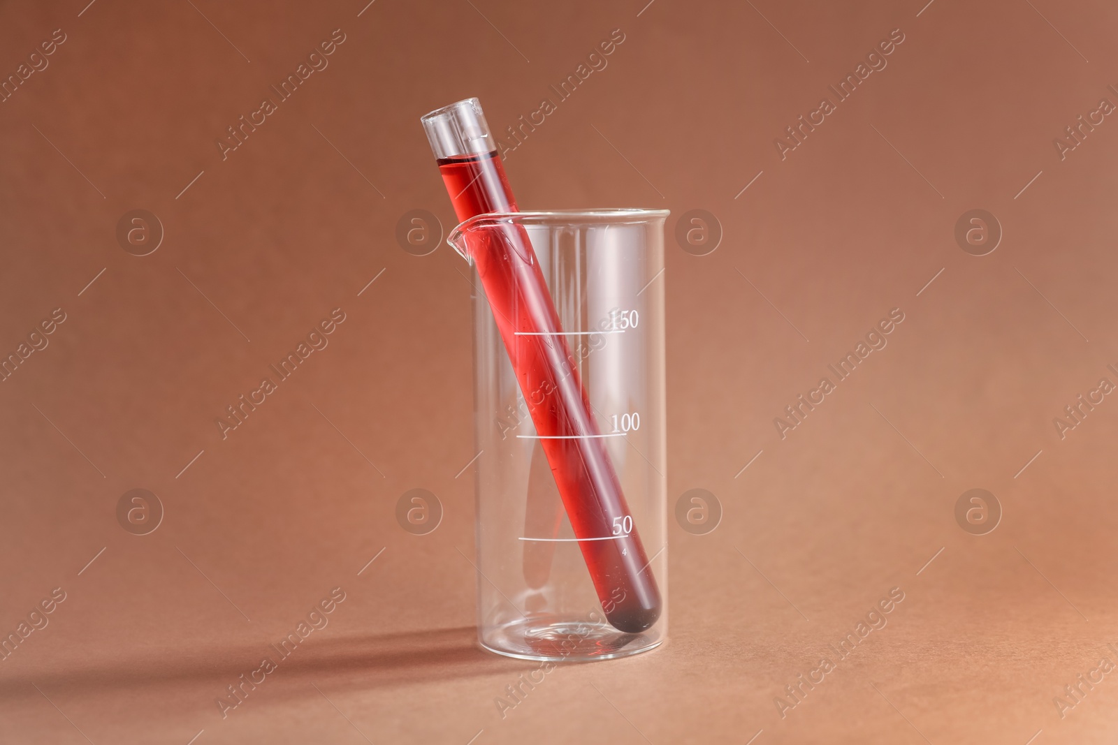 Photo of Laboratory glassware with red liquid on color background