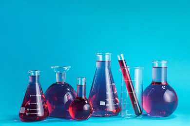 Photo of Laboratory glassware with color liquid on light blue background. Space for text