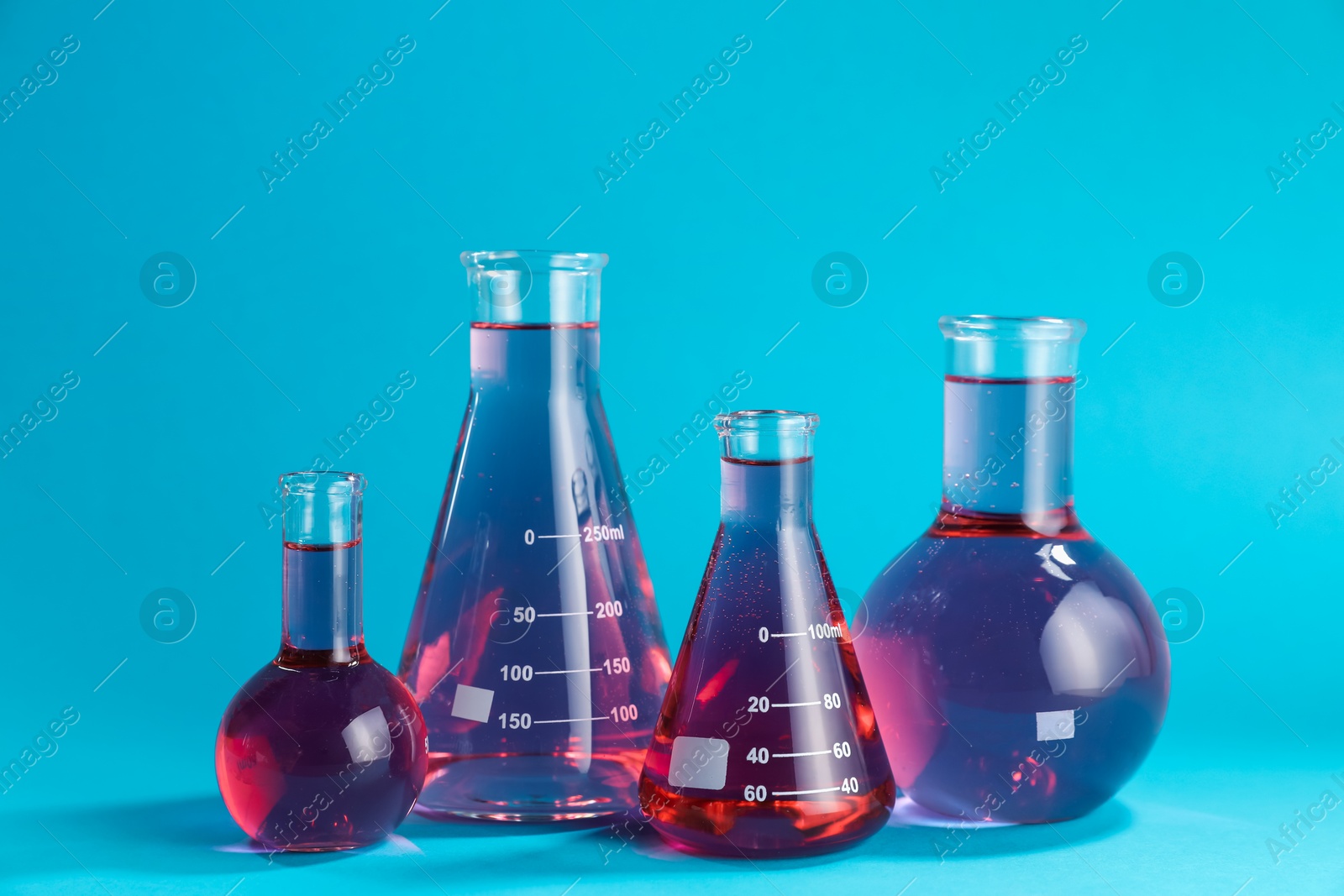Photo of Laboratory glassware with color liquid on light blue background