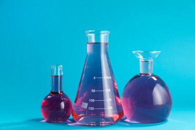 Photo of Laboratory glassware with color liquid on light blue background