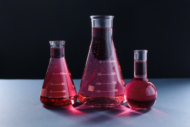 Photo of Laboratory glassware with red liquid on table against black background