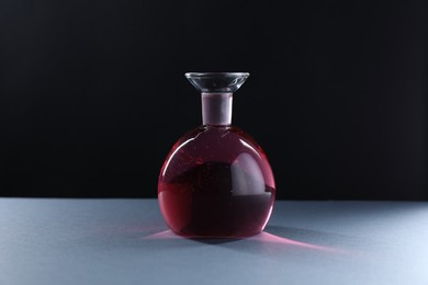 Photo of Flask with red liquid on table against black background