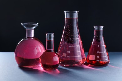 Photo of Laboratory glassware with red liquid on table against black background