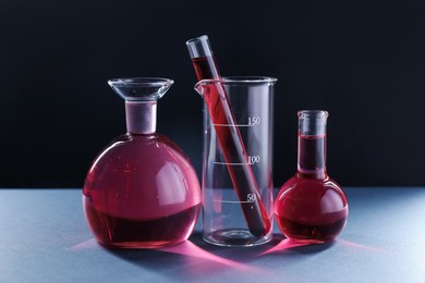Photo of Laboratory glassware with red liquid on table against black background