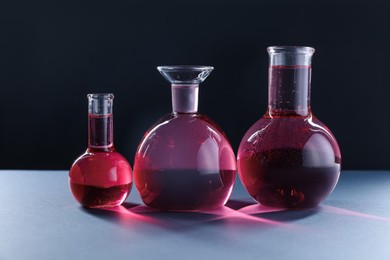 Photo of Laboratory glassware with red liquid on table against black background