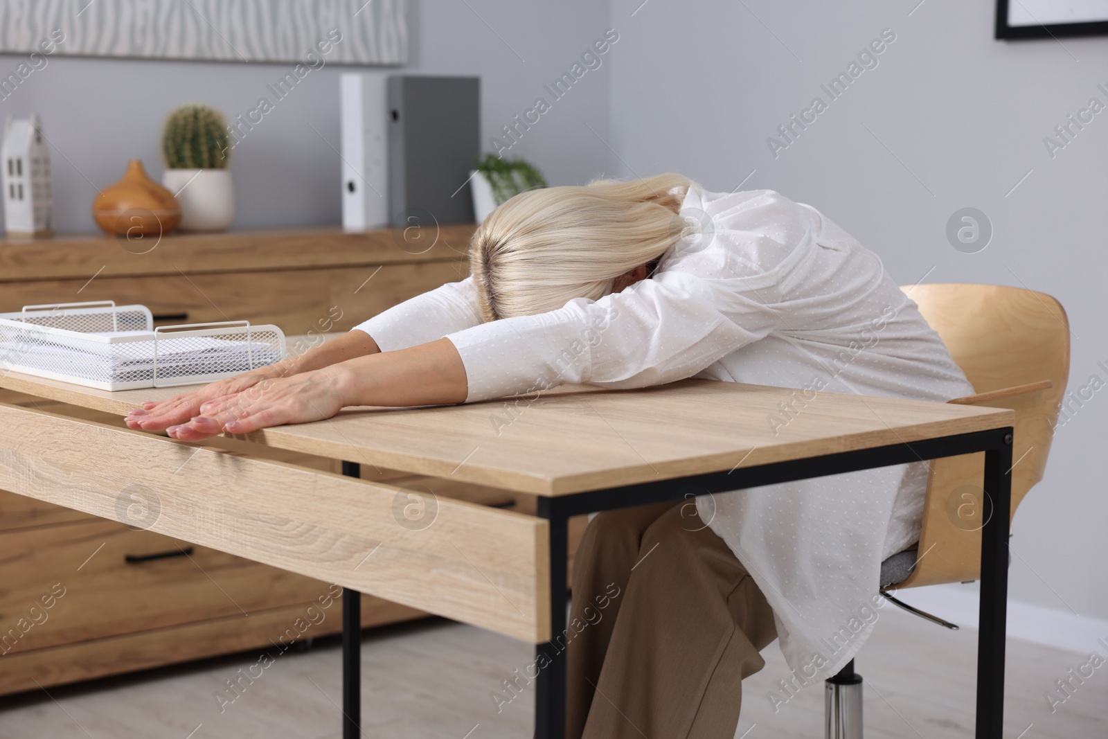 Photo of Mature woman stretching at table in office