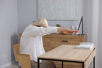 Photo of Mature woman stretching at table in office
