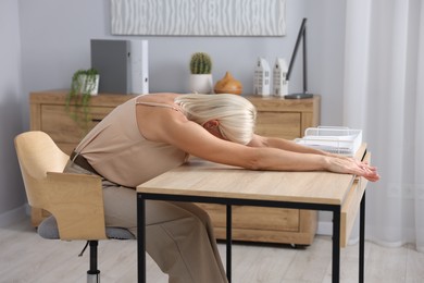 Photo of Mature woman stretching at table in office
