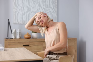 Photo of Mature woman stretching at table in office