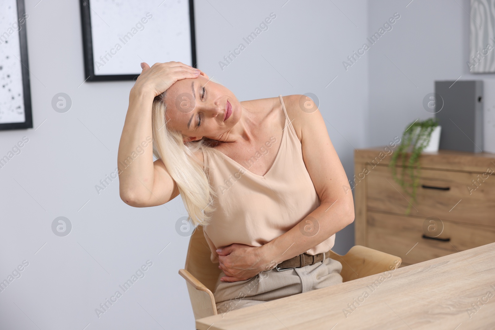 Photo of Mature woman stretching on chair in office