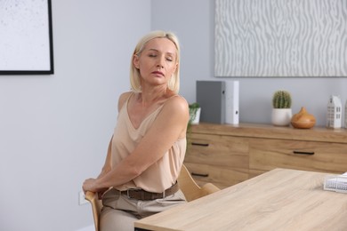 Photo of Mature woman stretching on chair in office