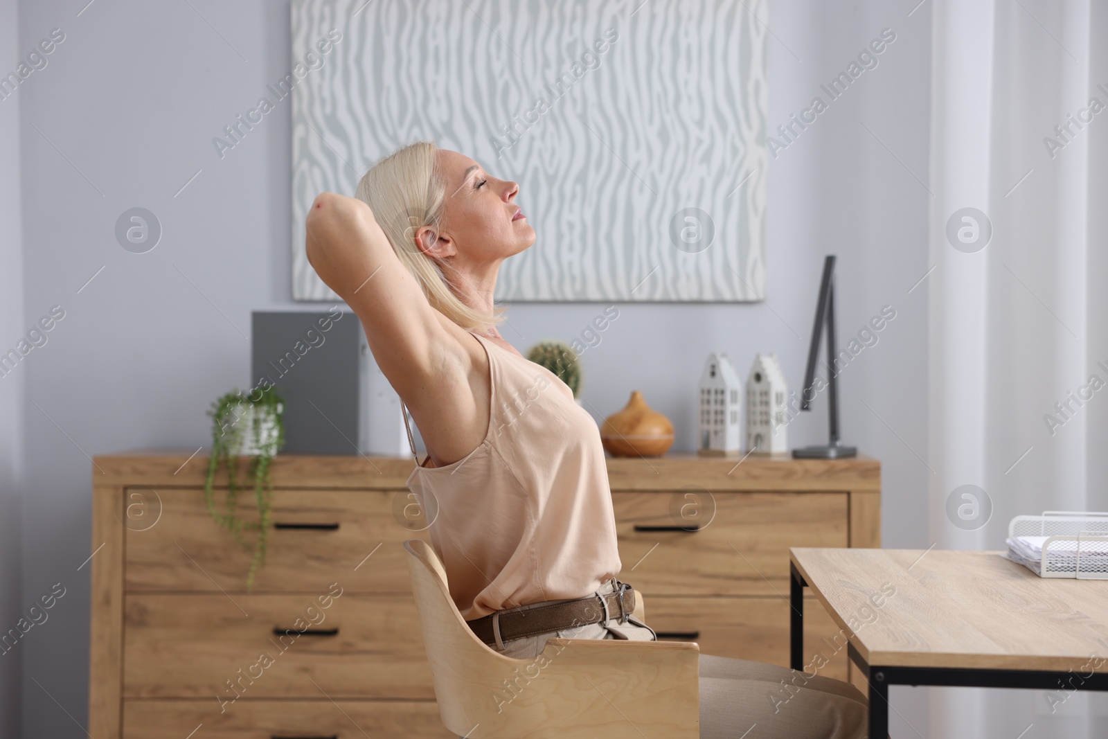 Photo of Mature woman stretching on chair in office