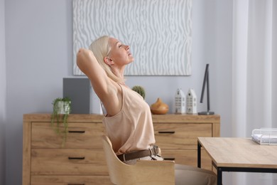 Photo of Mature woman stretching on chair in office