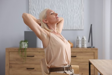 Photo of Mature woman stretching on chair in office