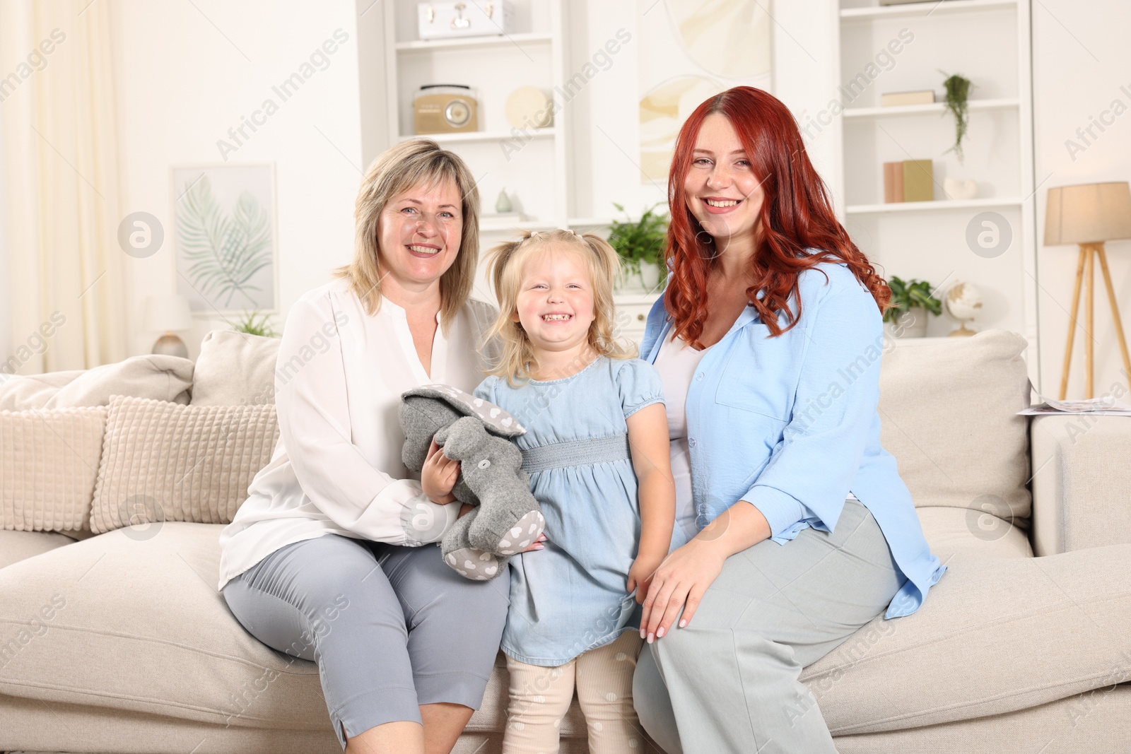 Photo of Pregnant woman, her mother and daughter on sofa at home