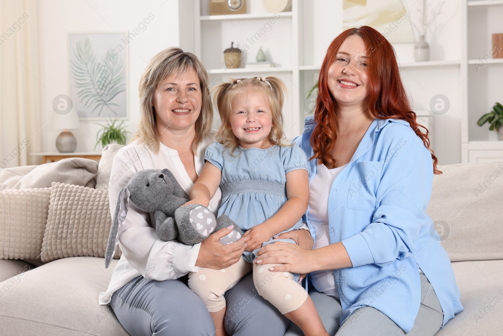 Pregnant woman, her mother and daughter on sofa at home Photo of Pregnant woman, her mother and daughter on sofa at home