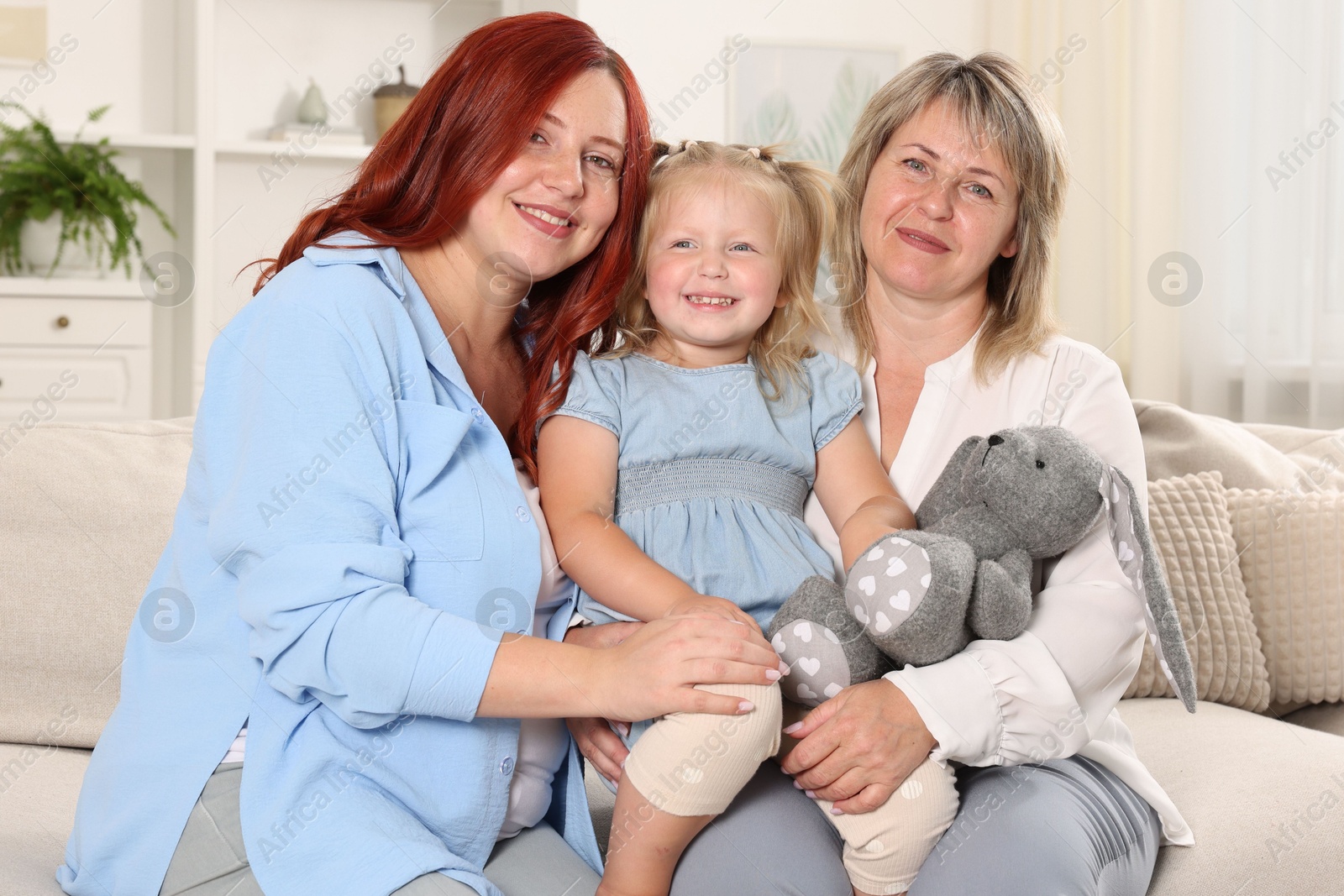 Pregnant woman, her mother and daughter on sofa at home Photo of Pregnant woman, her mother and daughter on sofa at home