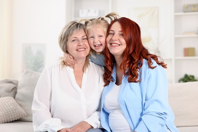 Photo of Pregnant woman, her mother and daughter on sofa at home