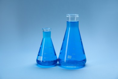 Photo of Flasks with bright liquid on light blue gradient background
