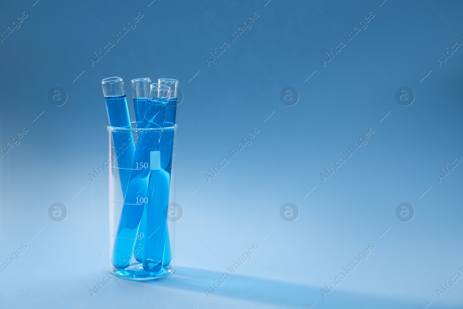 Test tubes with bright liquid on light blue gradient background. Space for text Photo of Test tubes with bright liquid on light blue gradient background. Space for text