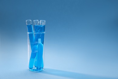 Photo of Test tubes with bright liquid on light blue gradient background. Space for text