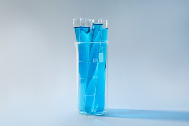 Photo of Test tubes with blue liquid on light background