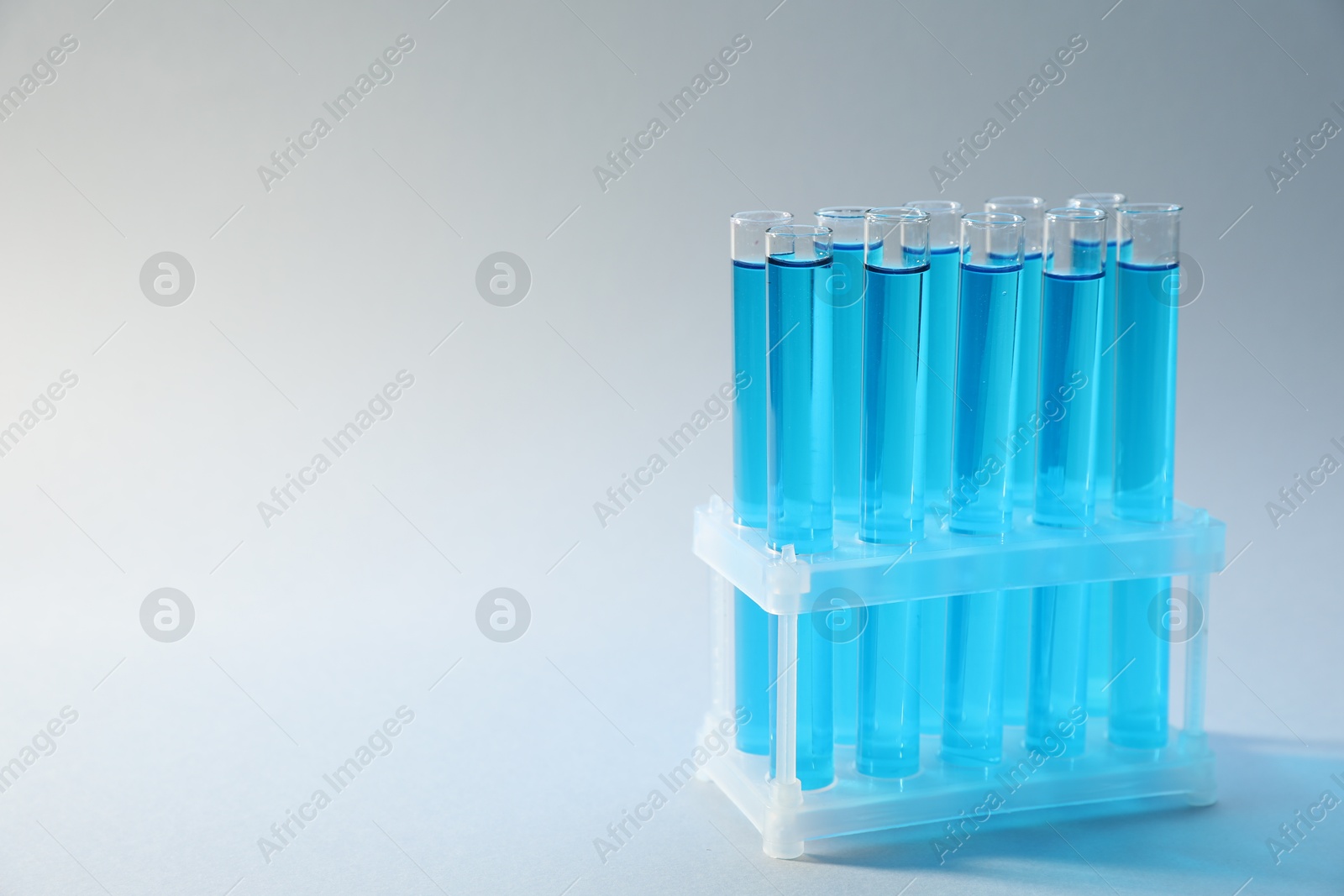 Test tubes with blue liquid on light background, closeup. Space for text Photo of Test tubes with blue liquid on light background, closeup. Space for text