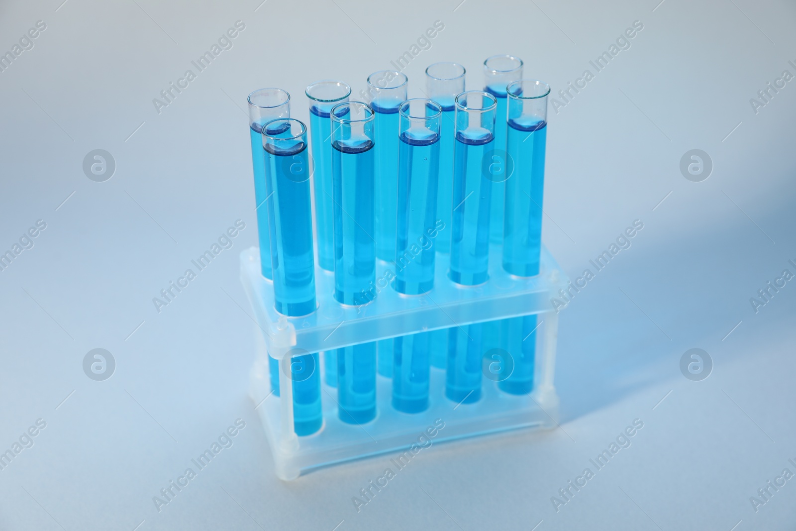 Photo of Test tubes with blue liquid on light background