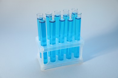 Photo of Test tubes with blue liquid on light background