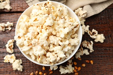 Photo of Tasty popcorn and corn kernels on wooden table, flat lay