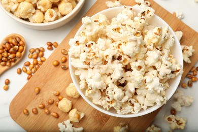 Photo of Tasty popcorn and corn kernels on white marble table, flat lay
