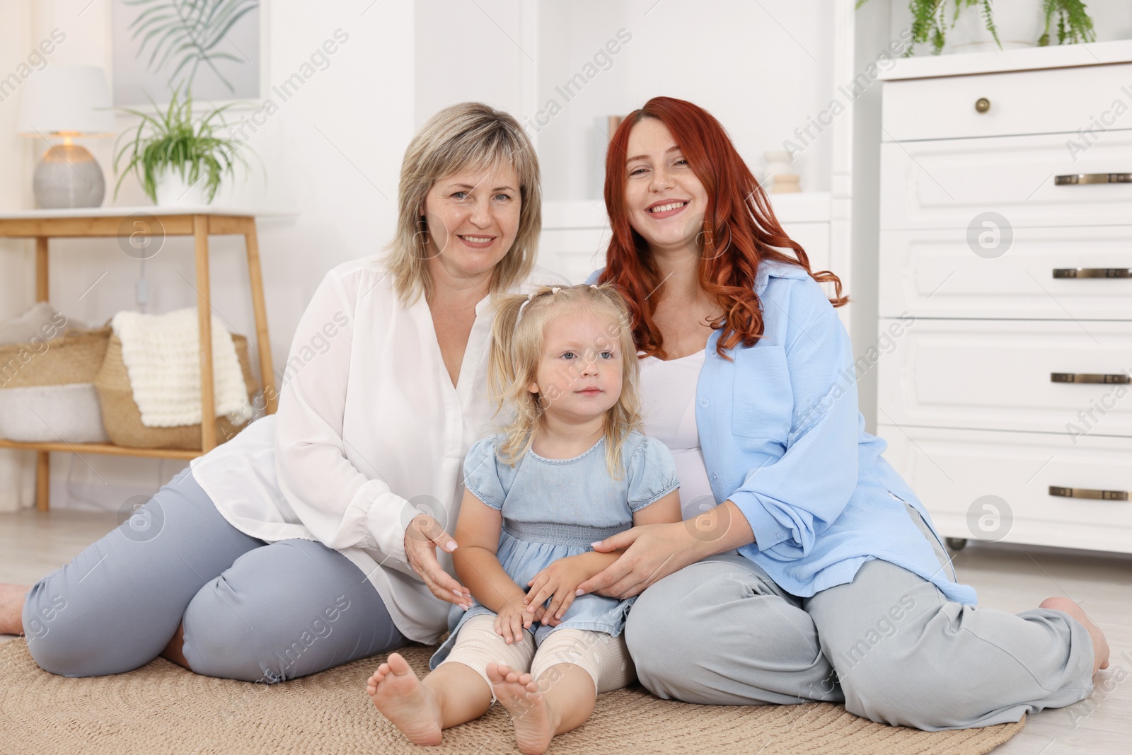 Pregnant woman, her mother and daughter on floor at home Photo of Pregnant woman, her mother and daughter on floor at home