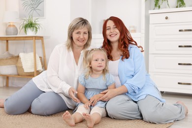 Photo of Pregnant woman, her mother and daughter on floor at home