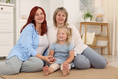 Photo of Pregnant woman, her mother and daughter on floor at home