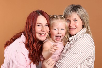 Photo of Grandmother, her daughter and granddaughter on brown background