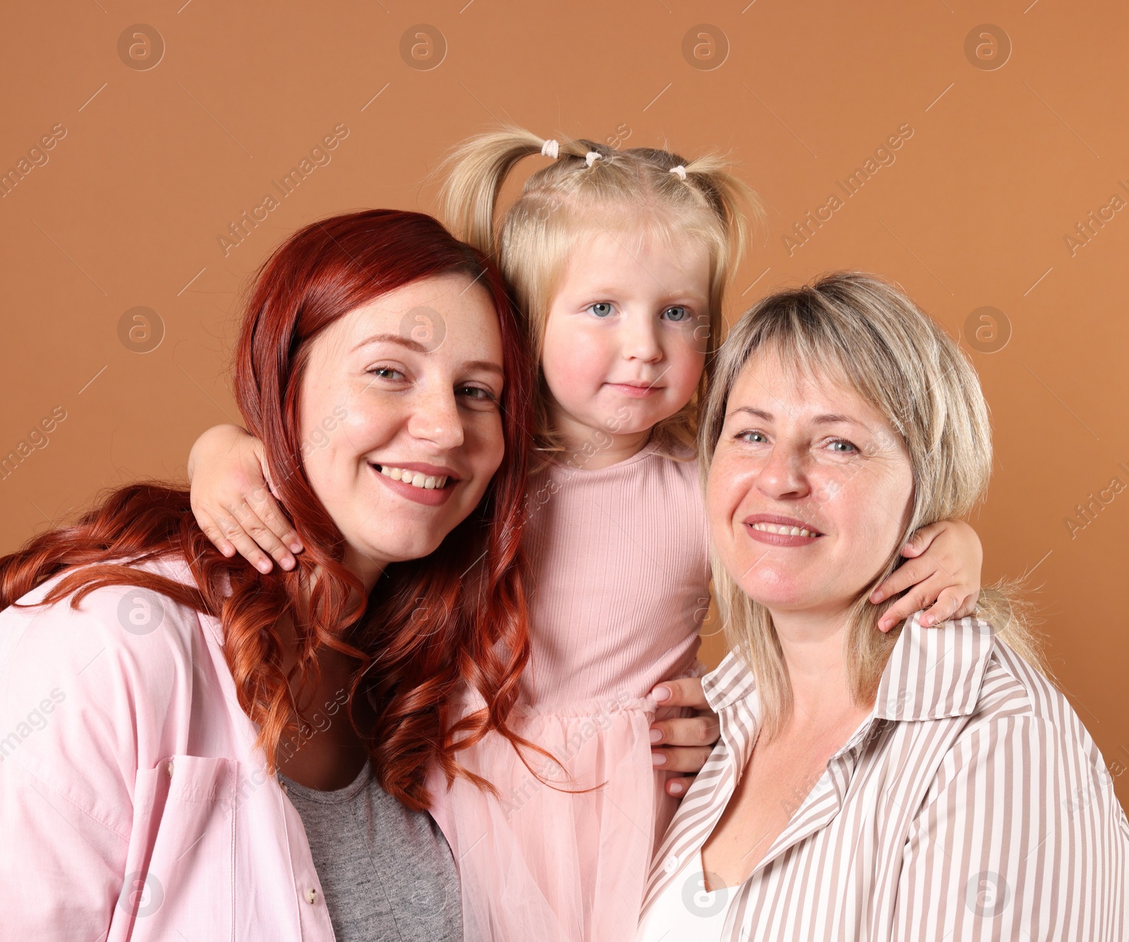 Grandmother, her daughter and granddaughter on brown background Photo of Grandmother, her daughter and granddaughter on brown background