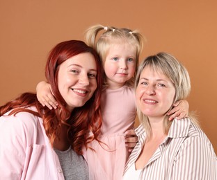 Photo of Grandmother, her daughter and granddaughter on brown background