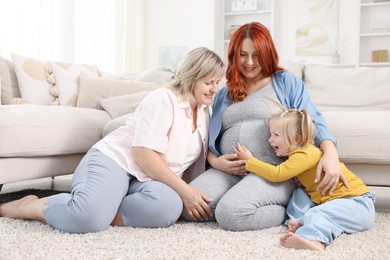 Photo of Pregnant woman, her mother and daughter on floor at home