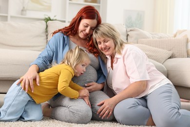 Photo of Pregnant woman, her mother and daughter on floor at home