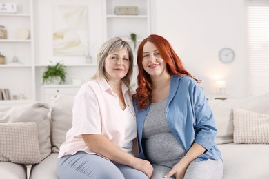 Photo of Pregnant woman and her mother on sofa at home