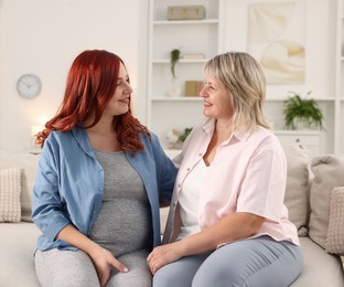 Photo of Pregnant woman and her mother on sofa at home