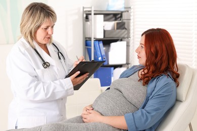 Photo of Pregnant woman having appointment with doctor in clinic