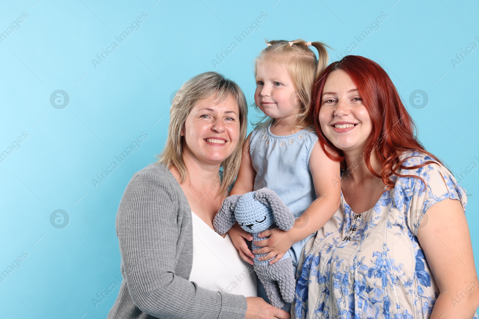 Grandmother, her daughter and granddaughter on light blue background Photo of Grandmother, her daughter and granddaughter on light blue background